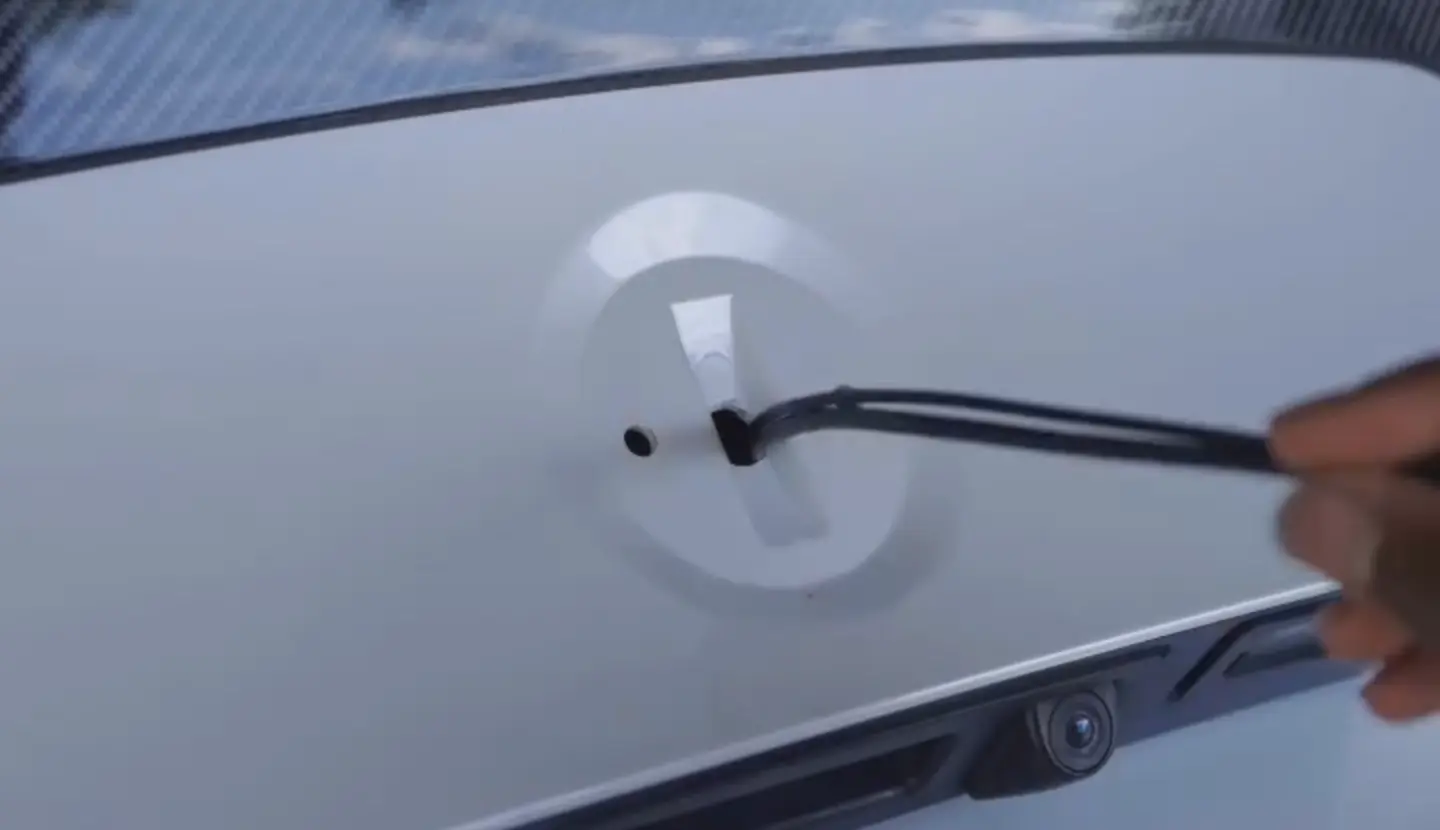 A cable being pushed through a hole made in a boot lid
